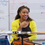 Black female teacher smiling at front of music classroom