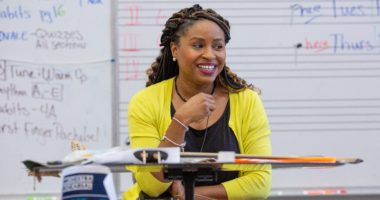 Black female teacher smiling at front of music classroom