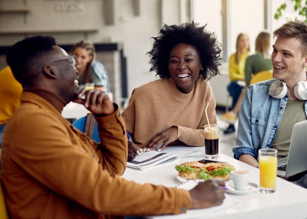 Black male and female and white male college student having a conversation at a table in cafeteria