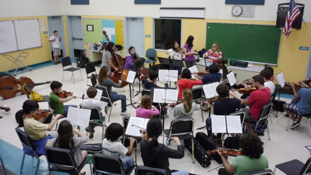 Students seated playing instruments in a music class in a classroom