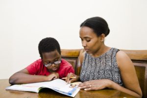 Black mother reads with her young son at home.