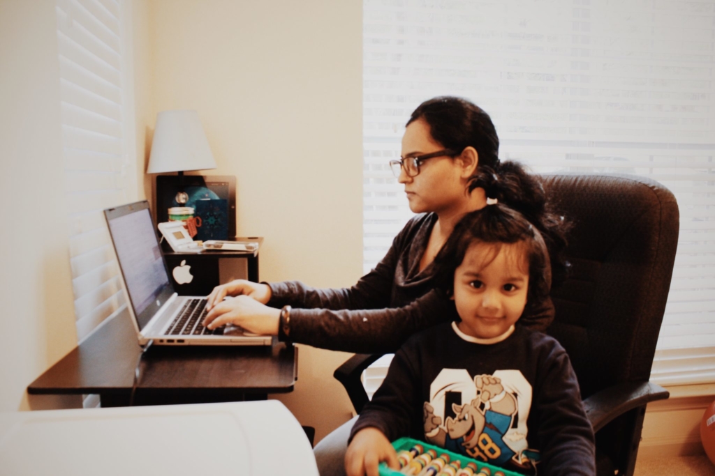 Busy mom working at desk with young daughter