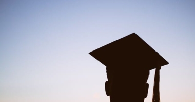 Sunset silhouette of male student wearing a graduation cap