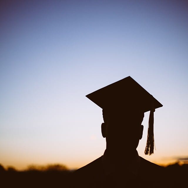 Sunset silhouette of male student wearing a graduation cap
