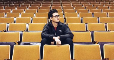 Male college student sitting alone in an auditorium
