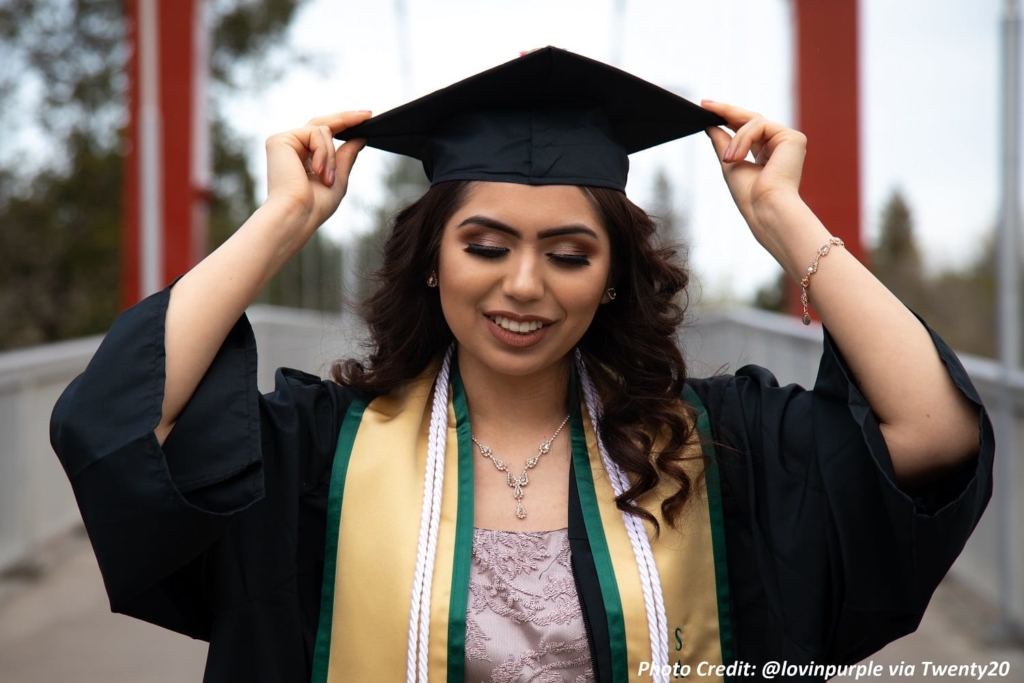 Hispanic female adjusting her graduation cap
