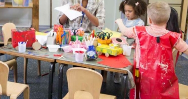 Pre-school teacher assisting pre-school kids with arts & crafts activities