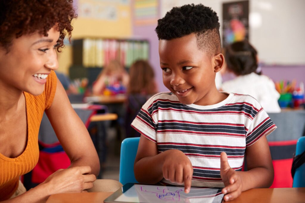 Black female teacher assisting a black male elementary student in classroom