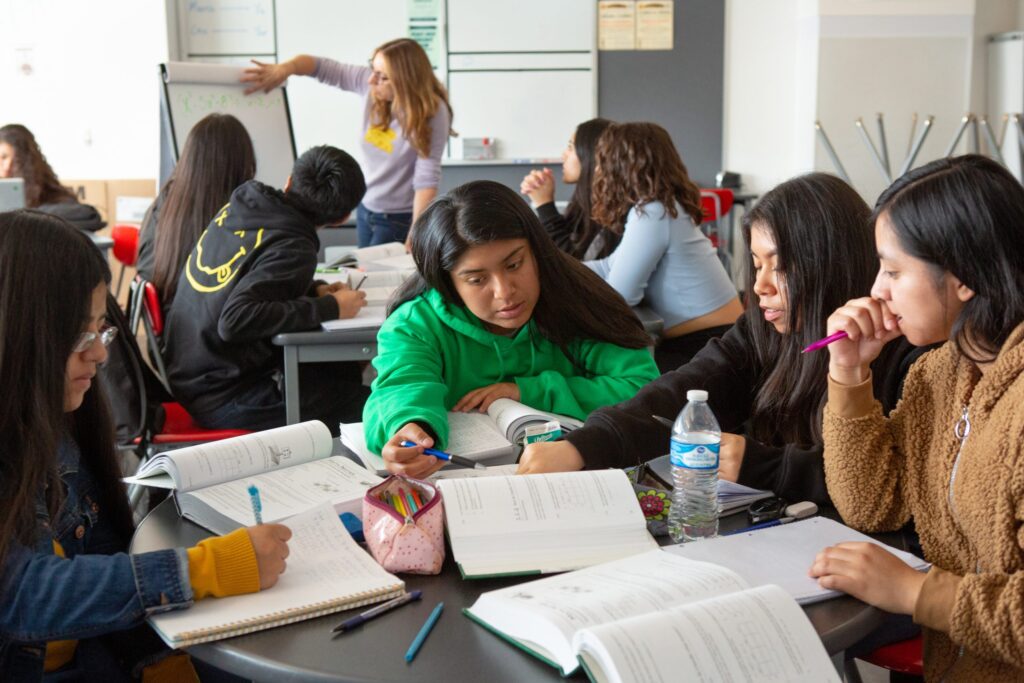 A group of students work together to solve problems in their textbook during class