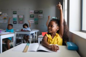 young black student raising her hand in a classroom