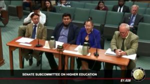 Three students and a legislator testifying at a legislative chamber sitting on a table