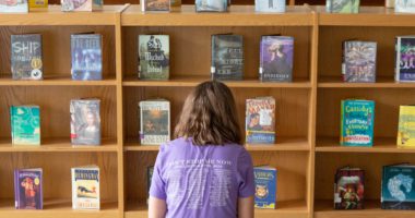 A seventh-grade student looks through books in her school library.