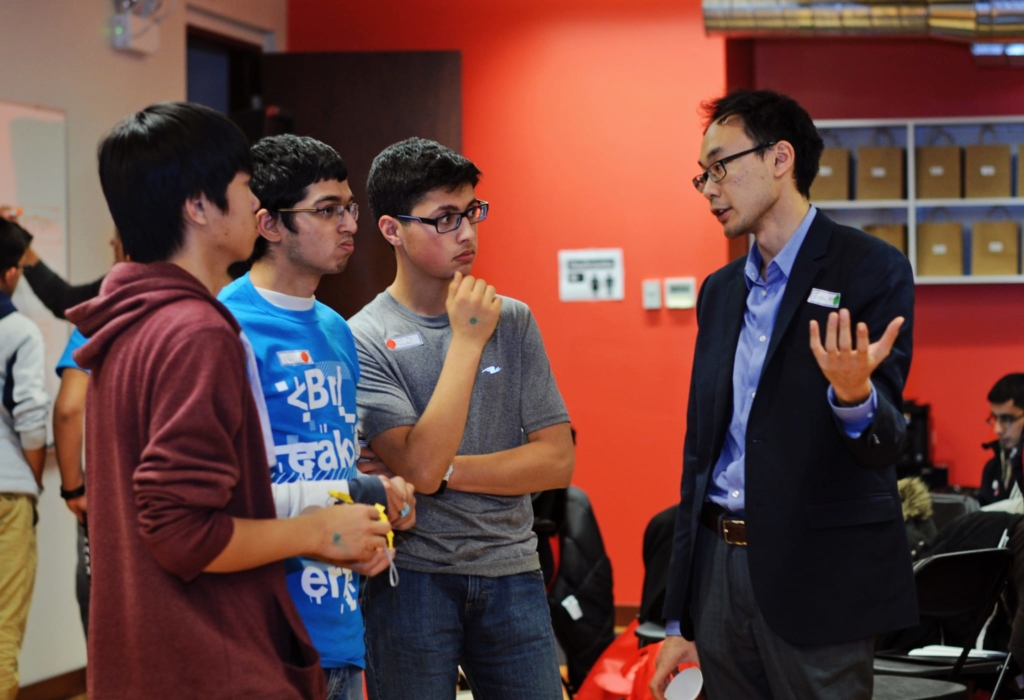 three male high school students talking to a teacher