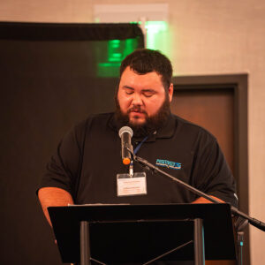 A male student speaking onstage to a microphone