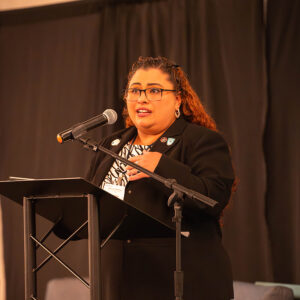 A female student onstage speaking to a microphone