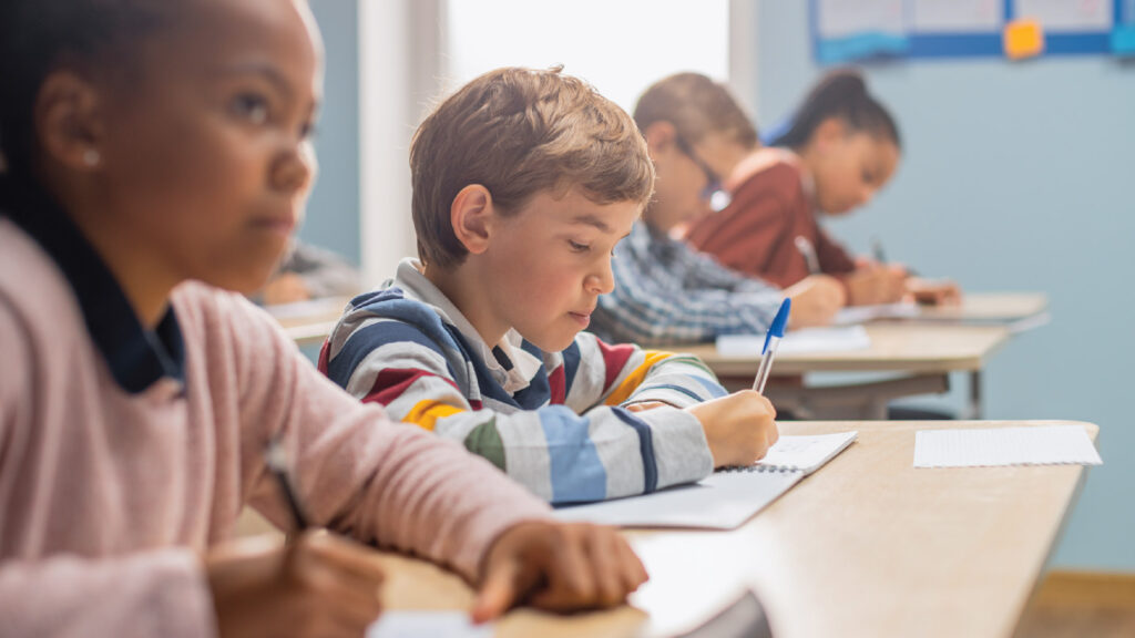 young students sitting at a desk doing schoolwork