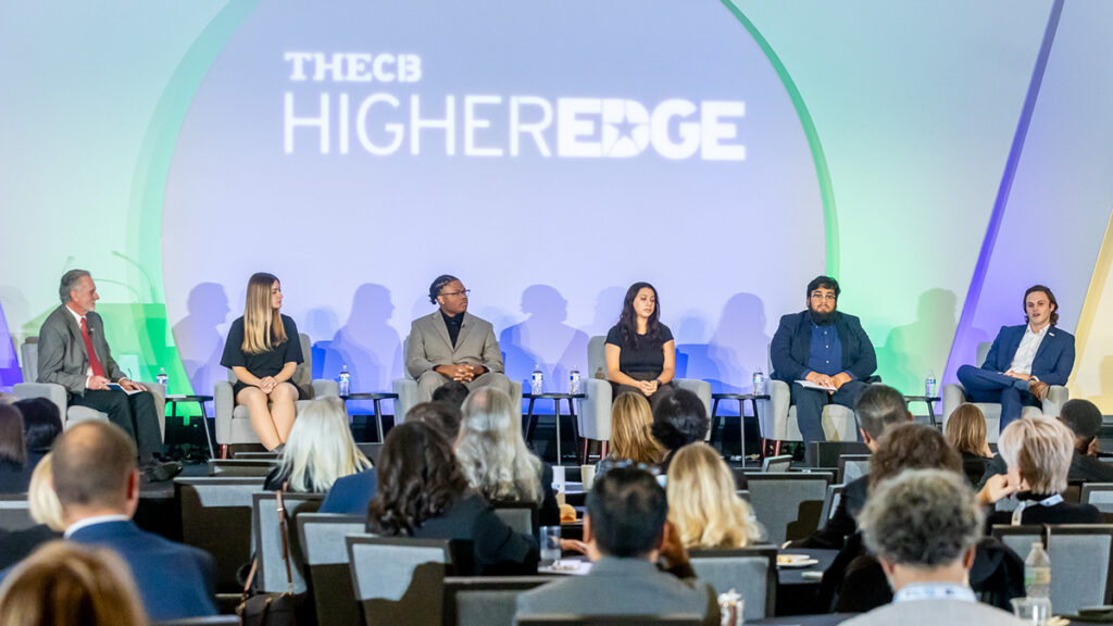 Six students wearing business attire on stage sitting with TheCB HigherEdge logo is above them