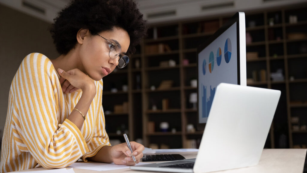 A black female college student studying with a laptop open in front of her