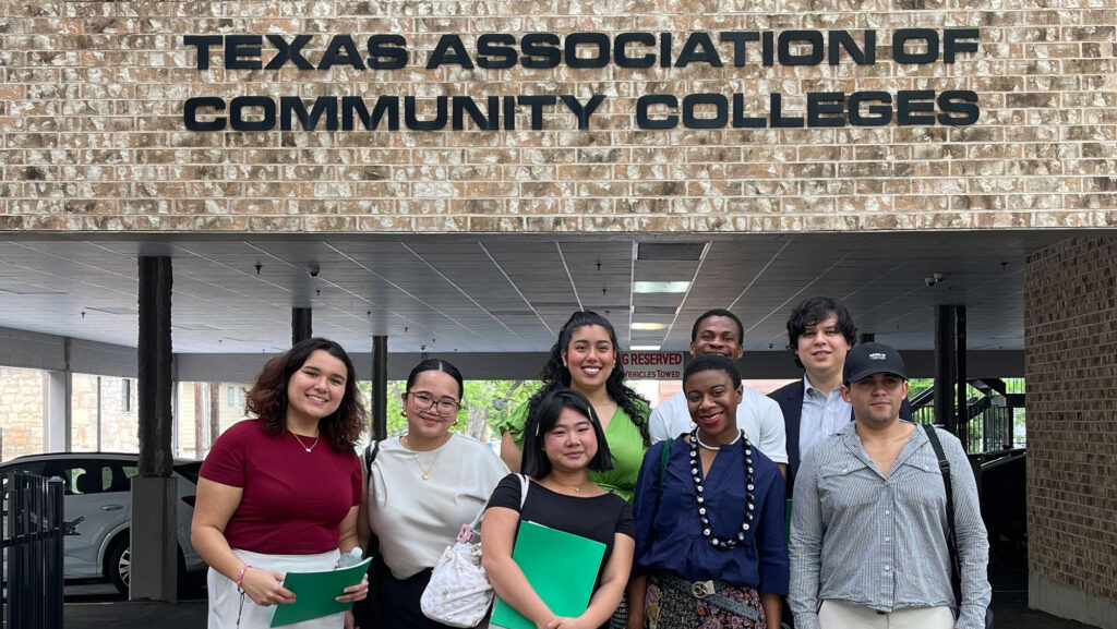 A group of young adults stands smiling in front of the Texas Association of Community Colleges building after the Student Advocacy in Action Convening .