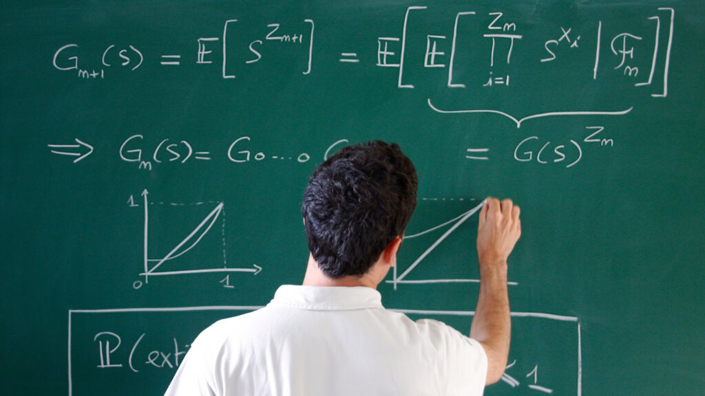 A male student writing a mathematical formula on a chalkboard