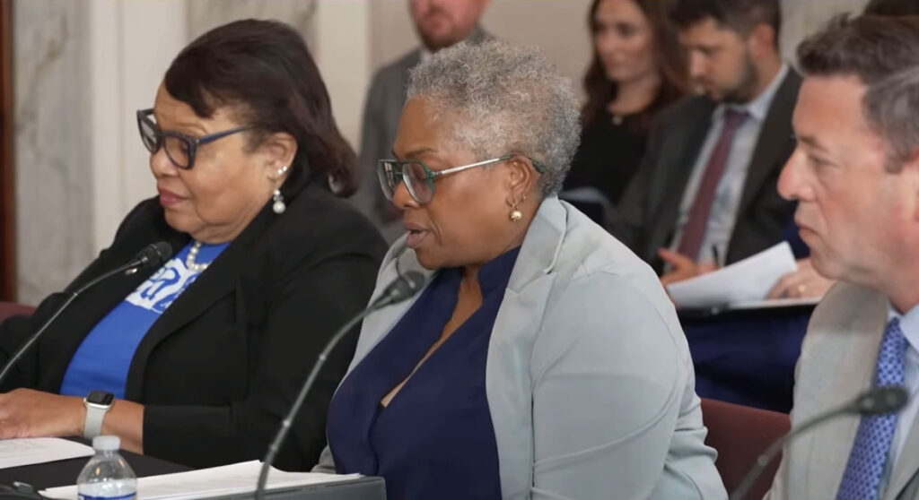 Denise Forte seated and speaking to a microphone with people seated next to her