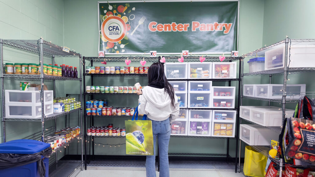 A student with a shopping basket looking at items at a food pantry on a college campus