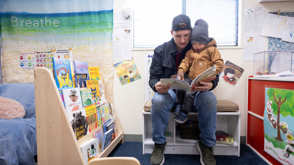 Father reading to his son during drop-off at a childcare center on a college campus.