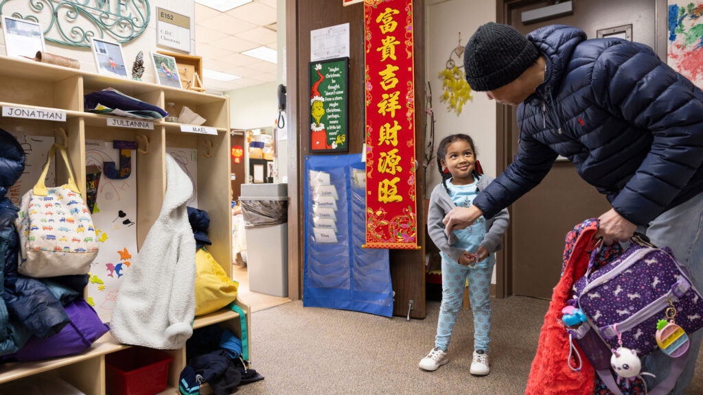 Father dropping off a young girl at a child care center on a college campus.